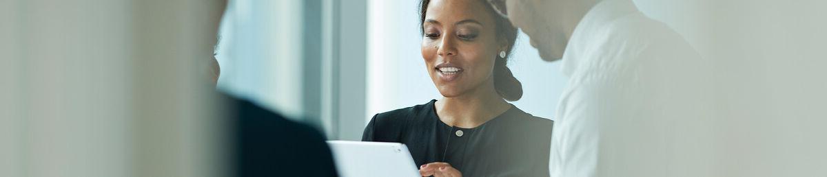 Two smiling colleagues standing together looking at an iPad